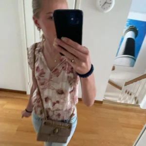 Blommig blus från Tamara H. - Säljer en söt blommig blus från Tamara H. i storlek S. Den har ett vackert blommönster i rosa och beige toner, med korta ärmar och en smockad kant längst ner. Passar till jätte mycket och köptes för runt 400 i usa 🥰