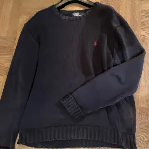 Säljer en snygg mörkgrå tröja från Polo Ralph Lauren i 100% bomull. Den har en klassisk design med ett rött broderat logotyp på bröstet. Perfekt för både höst och vinter, och passar till alla tillfällen. Tröjan är i mycket bra skick och redo för en ny ägare!