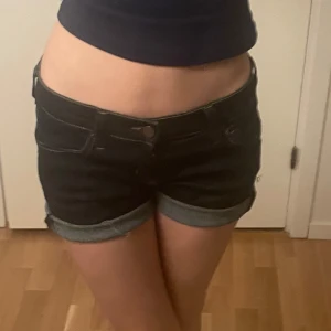 Svarta jeansshorts - Säljer ett par snygga mörkblå jeansshorts i bra skick. De är lågmidjade med en tight passform och har uppvikta ben. 