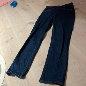 Mörkblå jeans i denim - Säljer ett par mörkblå jeans i klassisk denim. De har en rak passform och är perfekta för både vardag och fest. Jeansen är i bra skick och har en hållbar design med fokus på mindre energiförbrukning. Perfekta för dig som vill ha en stilren look!