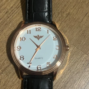 Elegant klocka - Säljer min fina klocka i toppskick! Den har knappt använts och är i mycket bra skick. Anledningen till försäljningen är att klockan är något för liten för mig.Specifikationer: 	•	Typ: Quartz	•	Färg: Roséguldfärgat hölje med svart läderband