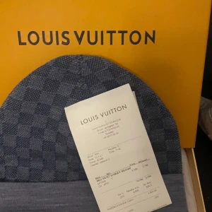 Blå mössa från Louis Vuitton - Säljer en mössa från Louis Vuitton. Den är i nytt skick och kommer i originalförpackning. Mössan har ett klassiskt rutmönster och en broderad LV-logga framtill. Perfekt för att hålla stilen i vinter!