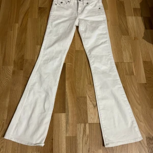 Vita bootcut jeans från True Religion - Säljer ett par snygga vita bootcut jeans från True Religion i storlek 24. De har en midwaist passform och är i mycket bra skick. Perfekta för både vardag och fest! 🕺✨