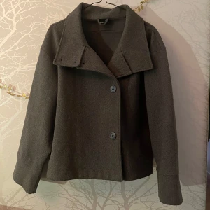 Grå kappa från Gina Tricot - Säljer en grå kappa från Gina tricot i storlek S!  Jackan har en klassisk design med stora knappar framtill och en bred krage och är även lite oversize. Använd ett fåtal gånger förra året