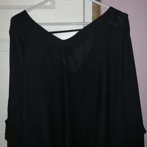 Svart blus - Snygg svart blus med en lös passform och kortärmad design. Perfekt för en stilren look. Stor i passform. Tunnt tyg och lite genomskinlig. Storlek är inte exakt passar från S- XL beroende på hur man vill att den sitter 