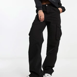 Svarta cargobyxor från Bershka - Snygga svarta cargobyxor från Bershka med rak passform och medelhög midja. Byxorna har praktiska fickor på sidorna och stängs med knapp och dragkedja. Perfekta för en avslappnad stil. Säljer eftersom att dom nu är för stora för mig. Endast använda någon enstaka gång. 