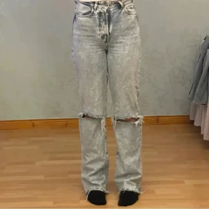 Jeans - Blå jeans med hög midja och slitna detaljer vid knäna från bik bok.