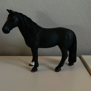 Schleich häst - En detaljerad svart hästfigur i plast med vita hovdetaljer. Perfekt för samlare eller som leksak för barn som älskar hästar. Hästen har en realistisk design med man och svans i samma svarta färg.