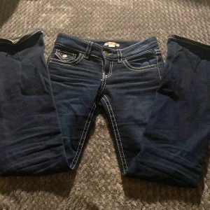 mörkblåa jeans med kontrastsömmar - snygga mörkblå jeans med kontrastsömmar och fina knappar på fickorna. ser som sagt ut skrynkligare och fulare på bilderna än i verkligheten som de andra gråa jeansen på min profil men är troligen väldigt fina och bra! använt runt 5-7 ggr men har inga fettfläckar eller fläckar alls, jeansen har spruckit lite längst ner på ett av benen men det går att sy eller bara inte bry sig om😅så det kommer inte skada jeansen mer. perfekt för en med size 152!