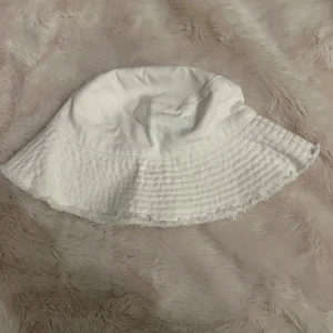 Vit bucket hat - Snygg vit bucket hat i bomullsmaterial. Perfekt för sommardagar med sin enkla och stilrena design. Passar bra till både strand och stad.