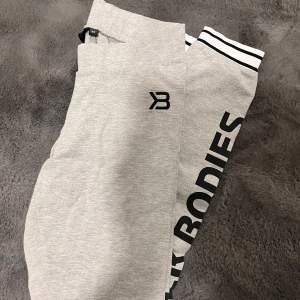 Snygga grå mjukis tights från  Better Bodies med svart logga längs benet. Byxorna har en elastisk midja med svarta ränder och är perfekta för en avslappnad stil.