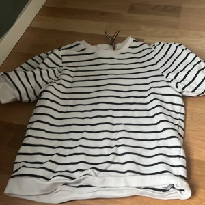 Randig tröja i bomull - Säljer en klassisk vit och svart randig tröja i bomull. Tröjan har en avslappnad passform med trekvartsärmar, perfekt för en stilren look. Passar bra till både jeans och kjol.