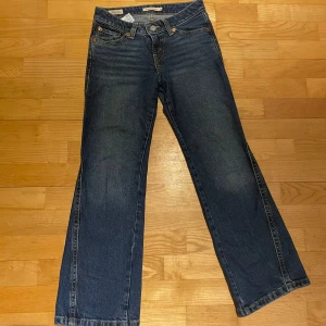 Levi's Bootcut Jeans - Snygga Levi's Noughties Bootcut jeans i klassisk blå denim. De har en låg midja och en bootcut-stil som ger en retro känsla. Perfekta för en avslappnad look med en touch av vintage. Köpte otroligt dyrt kosta säker mer än 1000kr.