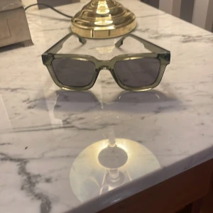 Gröna solglasögon från Komono - Snygga gröna solglasögon från Komono med en stilren design. Bågarna är i en transparent grön nyans och glasen är mörka. Perfekta för att ge en cool touch till din stil.