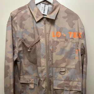 Beige camouflagejacka från Collusion - Säljer en beige camouflagejacka från Collusion med orange textdetaljer.