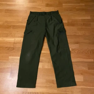 Gröna cargobyxor - Ett par Cargobyxor från 90-talet och är ett par polska militärbyxor. Bra skick och skön passform. Passar storlek 32. General wear, skick enligt bilderna.