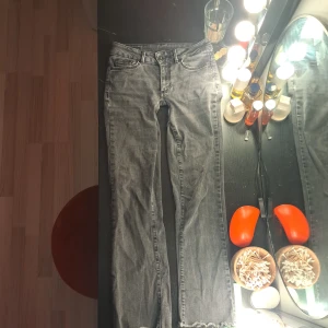Grå jeans med slitna detaljer - Säljer ett par grå jeans i bra skick. De har en straight passform och är lågmidjade. Jeansen har slitna detaljer vid bensluten som ger en cool look. Perfekta för både vardag och fest!
