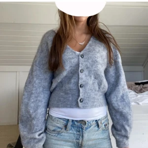 Grå kofta  - Mysig grå kofta från Lindex i storlek S. Den är stickad och har en v-ringad design med knappar framtill. Perfekt för höst och vinter, och funkar både till vardags och lite finare tillfällen. Superbekväm och lätt att matcha med olika outfits! 💫