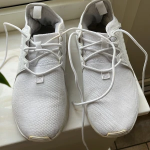 Vita sneakers från Adidas - Säljer ett par vita Adidas sneakers i bra skick. De har en stilren design med snörning och är perfekta för vardagsbruk. Skorna har en vit sula med bra grepp och är märkta med 'ALEXANDRA' på sidan. Perfekta för både vår och sommar!