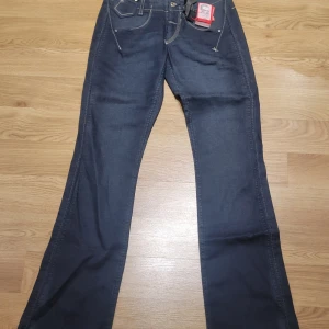 Mörkblå jeans från Girbaud - Säljer ett par snygga mörkblå jeans från Girbaud i storlek 26. De har en klassisk femficksdesign med coola sömdetaljer på bakfickorna. Jeansen är i nytt skick med etikett kvar. Perfekta för både vardag och fest!