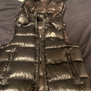 Moncler väst  - Säljer en svart dunväst från Moncler i mycket bra skick. Perfekt för höst och vinter, håller dig varm och stilren.       Passar både till vardags och lite finare tillfällen. Storlek 3 ungefär M/L