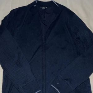 Mörkblå kofta från Callaway - Säljer en snygg mörkblå kofta från Callaway i mycket bra skick. Den har en dragkedja framtill och är perfekt för både höst och vinter. Koftan är långärmad och gjord i ett mjukt material som håller dig varm och bekväm. Perfekt för golf eller en avslappnad dag ute. Stolek XL men Sitter som M-L, Aldrig använd. Nypris 1199-: mitt pris 350!