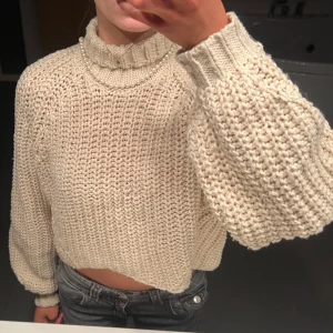 Stickad jättefin hösttröja  - Superfin beige stickad tröja med en croppad passform. Den har långa ärmar och en mysig, ribbad polokrage. Perfekt för höst och vinter när du vill hålla dig varm och stilren. Passar både till jeans och kjol för en avslappnad look. Säljes då den inte kommer till användning!