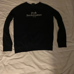 Svart tröja från Peak Performance - Säljer en svart tröja från Peak Performance i bra skick. Den har en klassisk design med vit text på framsidan. Perfekt för både vardag och chill. Passar bra till jeans eller träningsbyxor. Hör av dig vid intresse! Säljer den för jag har växt ur den. Nypris 800
