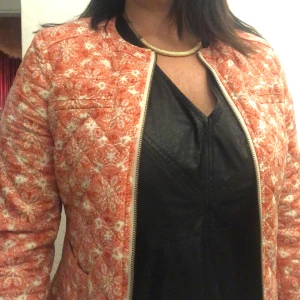 Orange mönstrad quiltad jacka - Säljer en superfin orange quiltad jacka med ett unikt mönster. Jackan har en dragkedja framtill och långa ärmar. Perfekt för höst och vår när du vill sticka ut lite extra. Den är i bra skick och redo för nya äventyr!