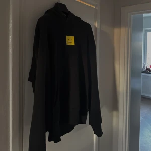 Svart hoodie från Acne Studios - Säljer en svart hoodie från Acne Studios i mycket bra skick. Den har en gul broderad patch med en liten missfärgning. Perfekt för höst och vinter, och den är superbekväm med sin normala passform. Ett måste för garderoben!