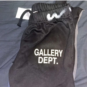 Svarta mjukisbyxor från Gallery Dept. - Säljer ett par svarta mjukisbyxor från Gallery Dept. med coola vita färgstänk. De har elastisk midja med snörning och sidofickor. Perfekta för en avslappnad stil eller chill dagar hemma. 🖤