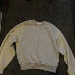 Grå sweatshirt - Säljer en enkel och bekväm grå sweatshirt i hyfsat bra skick. Perfekt för vardagsbruk. Den är ifrån Gina Tricot i storlek S. Den är lite nopprig och har nån tråd som låsnat lite men inget som märkts av när man har på den. Annars super fint skick. 