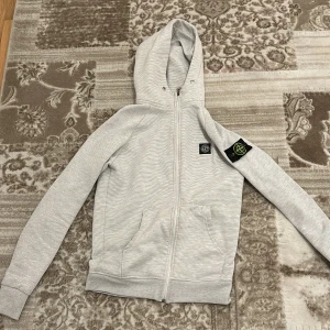  stone island  - Säljer en snygg grå hoodie från Stone Island. Den är i storlek M men passsr både S för jag har storlek S i koftor o den passar mig bra och den är ganska skön och sitter bra på än pris kan diskuteras 