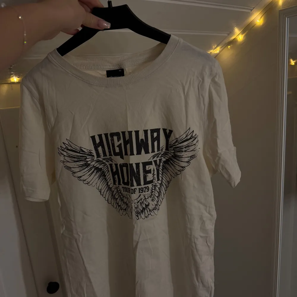 Säljer en vit t-shirt med coolt tryck 'Highway Honey Tour of 1979' och vingar. Perfekt för en avslappnad stil. Storlek XS.       Pris 50:- 🌟. T-shirts.