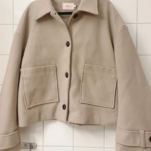 Beige jacka från Nelly - Säljer en superfin beige jacka från Nelly. Den har en stilren design med stora fickor och knappar framtill. Perfekt för höst och vår! Jackan är i mycket bra skick och passar till både vardag och fest. 🧥✨