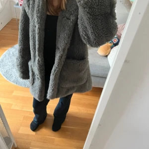 Grå teddyjacka från H&M - Supermysig grå teddyjacka från H&M i storlek XS. Perfekt för kyliga höst- och vinterdagar. Jackan har långa ärmar och stängs med knappar framtill. Den har också stora fickor för extra komfort och stil.