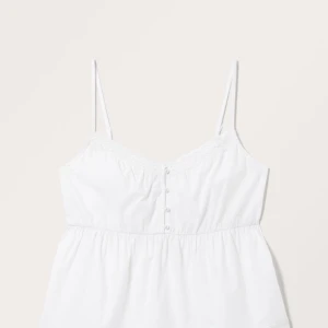 Snygg topp - Säljer ett superfint vitt linne med spetsdetaljer och knappar framtill. Perfekt för sommardagar eller som ett sött lager under en kofta. Axelbanden är smala och linnet har en luftig passform. Passar både till vardags och fest!