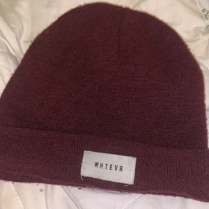 Vinröd mössa från Gina Tricot  - Säljer en snygg vinröd mössa från Gina tricot. Den är stickad och perfekt för kyliga dagar. Mössan har en enkel design med en liten etikett framtill. Passar både till vardags och lite mer avslappnade tillfällen. Perfekt för höst och vinter! Välanvänd men ser ut som ny.