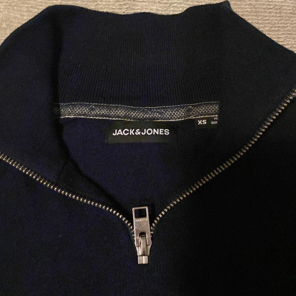 Säljer en stilren navy tröja från Jack & Jones i storlek XS, fits S. Tröjan har en praktisk dragkedja vid halsen och är perfekt för både vardag och fest. Passar perfekt till jeans för en avslappnad look. . Tröjor & Koftor.