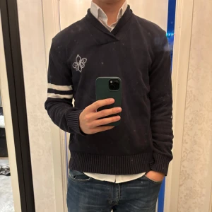 Mörkblå tröja från Morris - Säljer en snygg mörkblå tröja från Morris i storlek M. Den har et broderat emblem på bröstet och vita ränder på ärmarna. Tröjan är i bra skick och perfekt för både höst och vinter. Passar bra till både vardag och fest!