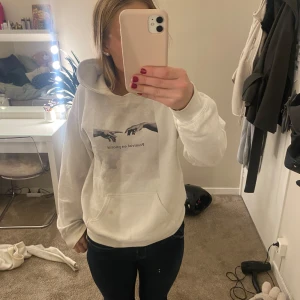 Vit hoodie med tryck - Säljer en vit hoodie i bra skick med ett coolt tryck på framsidan. Den har en stor ficka fram och en bekväm huva. Perfekt för en avslappnad stil och passar till alla årstider. Storleken är normal och den är supermjuk och skön att ha på sig.