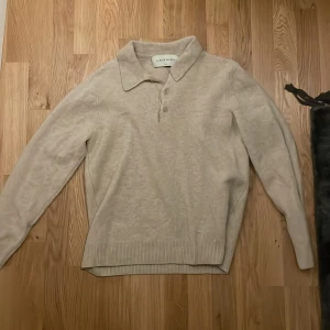 Beige tröja från A Day's March - Säljer en stilren beige tröja från A Day's March i storlek Large. Tröjan har en klassisk krage och knappar framtill. Perfekt för både höst och vår, med långa ärmar och ribbade kanter som ger en snygg passform. Passar både till vardags och lite finare tillfällen.