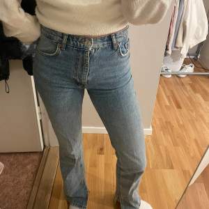 Säljer ett par snygga blå jeans i mycket bra skick. De är högmidjade och har en straight passform. Jeansen har en cool slitsdetalj vid anklarna som ger en trendig touch. Perfekta för både vardag och fest! (Sömmarna där man sätter skärpet har lossnat vid båda sidor av midjan men det är inget som syns)