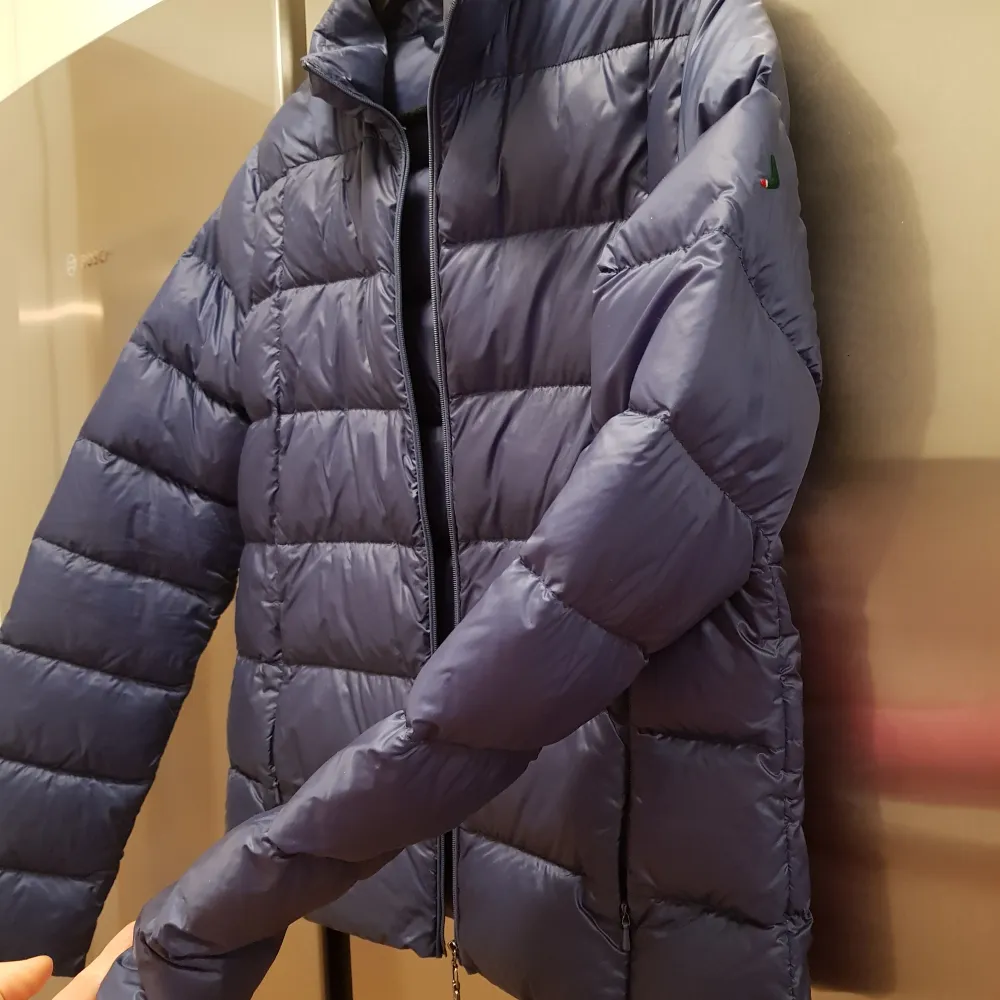 Säljer en snygg blå dunjacka från Boomerang i mycket fint skick. Perfekt för kalla vinterdagar med sin varma och puffiga design. Jackan har en dragkedja framtill och långa ärmar. Den är i en klassisk stil som passar till det mesta. Perfekt för både vardag och utomhusaktiviteter.. Takit.