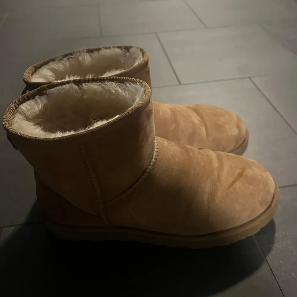 Mysiga bruna UGG boots i mocka med varmt foder. Perfekta för kalla dagar när du vill hålla fötterna varma och bekväma. De har en klassisk design med rund tå och är i bra skick. Passar perfekt till höst- och vinteroutfits!. Skor.