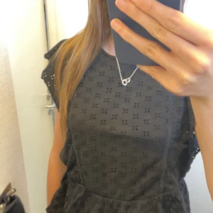 Svart tröja med broderade detaljer - Säljer en superfin svart tröja med broderade detaljer. Den har korta ärmar och ett sött mönster som ger en romantisk touch. Perfekt för både vardag och fest.