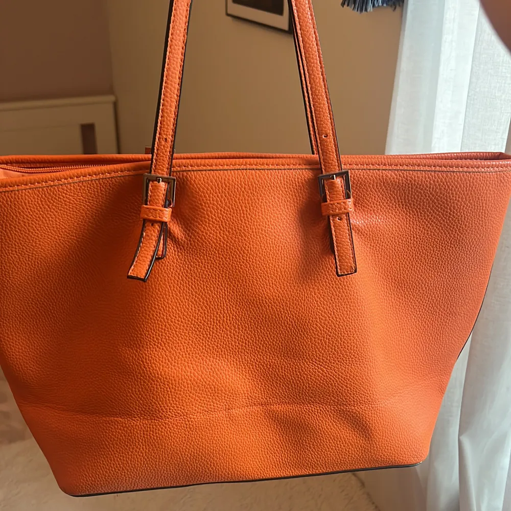 Säljer en snygg orange axelväska från Michael Kors i bra skick. Väskan har justerbara remmar och ett rymligt inre med flera fack, perfekt för vardagsbruk. Den är gjord av skinn och har en stilren design med en liten logotypdetalj framtill. Säljer då jag inte använder längre. . Väskor.