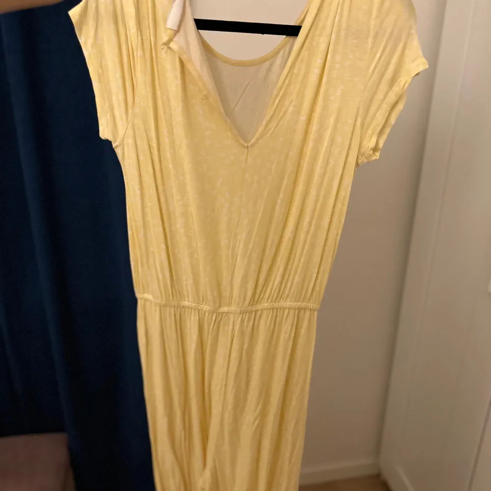 Säljer en superfin gul jumpsuit i mjukt material. Den har korta ärmar och en bekväm passform med resår i midjan. Perfekt för sommardagar eller avslappnade tillfällen. Färgen är ljus och fräsch, vilket gör den idealisk för varma dagar.. Klänningar.