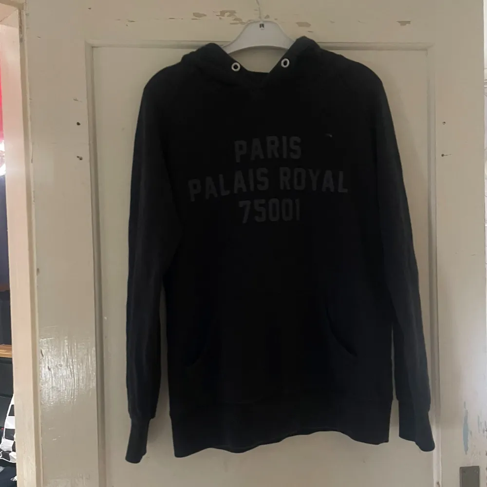 Säljer en svart hoodie från Balzac Projects i storlek S. Den har texten 'PARIS PALAIS ROYAL 75001' tryckt på framsidan. Perfekt för en casual look och superbekväm att ha på sig. Hör av dig om du är intresserad! 🖤. Neuletakit & Villapaidat.