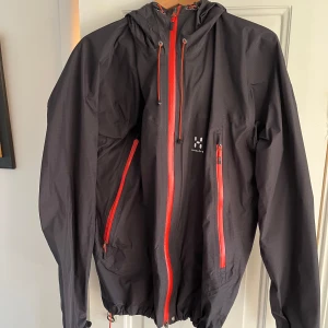 Haglöfsjacka  - Vindjacka från Haglöfs i bra skick. Dock har det släppt lite i luvan som man ser på bilden. Går lätt att limma med textillim. 